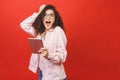 Excited amazed young beautiful woman with tablet pc. Happy girl in white shirt using tablet computer, isolated on red background Royalty Free Stock Photo