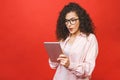 Excited amazed young beautiful woman with tablet pc. Happy girl in white shirt using tablet computer, isolated on red background Royalty Free Stock Photo