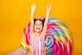 excited arab child girl in colorful striped dress raising her arms in the air having fun on yellow background Royalty Free Stock Photo