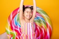 excited arab child girl in colorful striped dress raising her arms in the air having fun on yellow background Royalty Free Stock Photo