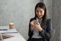 Excited asian business girl while reading a smart phone sitting