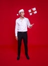 Excited asian business man wearing Santa hat and looking surprise with the falling gift box on hand. on over red background