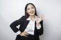 Excited Asian business woman wearing a black suit giving an OK hand gesture isolated by a white background Royalty Free Stock Photo