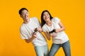 Excited asian couple playing video game with joysticks