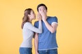 Excited Asian couple whispering secrets to each other isolated on yellow background Royalty Free Stock Photo