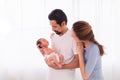 Excited Asian father with beard hold his first child newborn with strong arm, beautiful wife play with baby and try to help Royalty Free Stock Photo