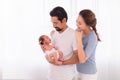 Excited Asian father with beard hold his first child newborn with strong arm, beautiful wife play with baby and try to help Royalty Free Stock Photo