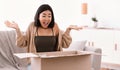 Excited asian woman unpacking parcel after online shopping