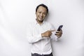 Excited Asian man wearing white shirt smiling while holding his phone, isolated by white background Royalty Free Stock Photo