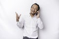 Excited Asian man wearing white shirt smiling while holding his phone, isolated by white background Royalty Free Stock Photo