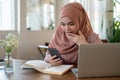An excited Asian-Muslim woman is looking at her smartphone screen with a surprising face Royalty Free Stock Photo