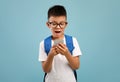 Excited Asian Schoolboy With Backpack Using Smartphone Over Blue Background Royalty Free Stock Photo