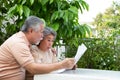 Excited Asian senior mature couple feeling amazed by good surprise news while reading newspaper.