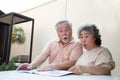 Excited Asian senior mature couple feeling amazed by good surprise news while reading newspaper .