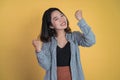 Excited asian woman clenching hands while celebrating success