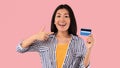 Excited asian woman holding and pointing at credit card Royalty Free Stock Photo