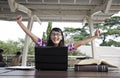 Excited asian woman with laptop and books