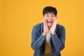 Excited asian young man hold hand mouth scream shout Royalty Free Stock Photo