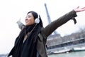 Excited asian young woman listening to music and enjoying moment in front of Eiffel tower in Paris.