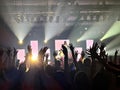 An excited audience at a concert with the lights flashing and the arms and hands raised in the air Royalty Free Stock Photo