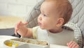 Excited baby girl touches food leftovers on plate and tastes