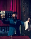 Excited barman luxury beverage concept. Man with beard holds glass with alcohol in bar. Waiter bartender in vintage vest