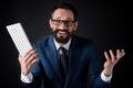 Excited bearded businessman in eyeglasses holding keyboard and looking at camera