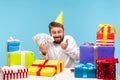 Excited bearded man in cone hat opening gift box and showing thumbs up receiving lot of dollar cash, satisfied with money bonus, Royalty Free Stock Photo