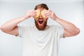 Excited bearded man covering eyes with hamburgers