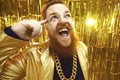 Excited bearded man in extravagant outfit with gold chain necklace having fun at a party