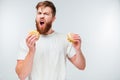 Excited bearded man greedily eating hamburgers