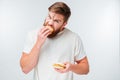 Excited bearded man greedily eating hamburgers