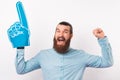 Excited bearded man is making the winner gesture while wearing foam fan glove. Royalty Free Stock Photo