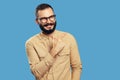 Excited bearded man smiling while pointing aside on empty space over blue