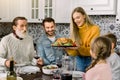 Excited beautiful family looking at thanksgiving turkey. Young woman holds the plate with roast chicken or turkey Royalty Free Stock Photo