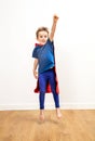 Excited beautiful little boy dressed like a powerful superhero jumping
