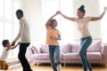 Excited biracial family with kids have fun dancing at home