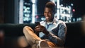 Excited Black African American Man Using Smartphone While Sitting on a Sofa in Living Room. Happy Royalty Free Stock Photo