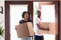 Excited black couple carrying boxes impressed entering new home