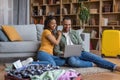 Excited black couple with laptop and travel suitcases planning holiday trip, booking tickets or looking for rentals Royalty Free Stock Photo