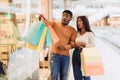 Excited black couple with shopping bags pointing at window Royalty Free Stock Photo