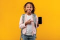 Excited black girl showing blank empty smartphone screen and pointing