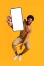 Excited black guy holding smartphone, jumping up