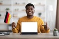 Excited black guy student showing flag of Germany and laptop