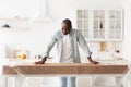 Excited black handyman ready to assembling wooden table by yourself after home relocation, looking at table and smiling