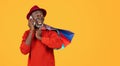 Excited black senior man in a red sweater and hat talking on the phone with a surprised expression Royalty Free Stock Photo