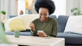 Excited black woman chatting in dating app using her phone at home. A young female online shopping happy about a Royalty Free Stock Photo