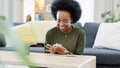 Excited black woman chatting in dating app using her phone at home. A young female online shopping happy about a Royalty Free Stock Photo