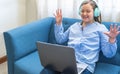 Excited blonde girl with her hands up sitting on a sofa with a laptop