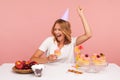 Excited blonde young adult female celebrating birthday, holding cake with candle, yelling happily, enjoying dream come true on her